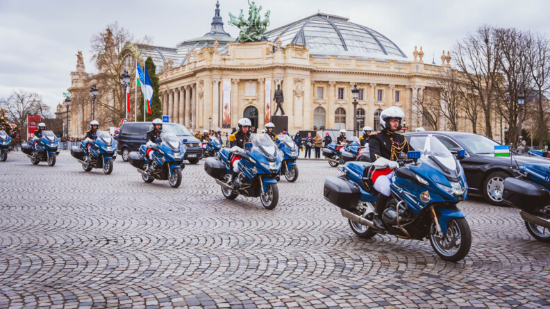 Devant le grad palais passent les motards de la Garde républicaine, escortant une berline noire arborant le drapeau de l'Ouzbékistan et un van noir