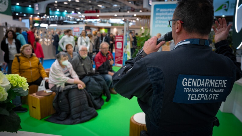 Agrandir l'image Un gendarme de dos devant une assemblée. Sur son dos est marqué "Gendarmerie des transports aériens - Télépilote".