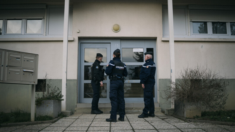 Agrandir l'image Trois gendarmes de dos devant une porte d'immeuble.