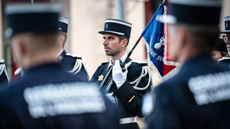 En amorce, deux gendarmes avec dans le dos et en flou, noté "Gendarmerie de l'armement". En second plan et net, un adjudant de cette même unité.