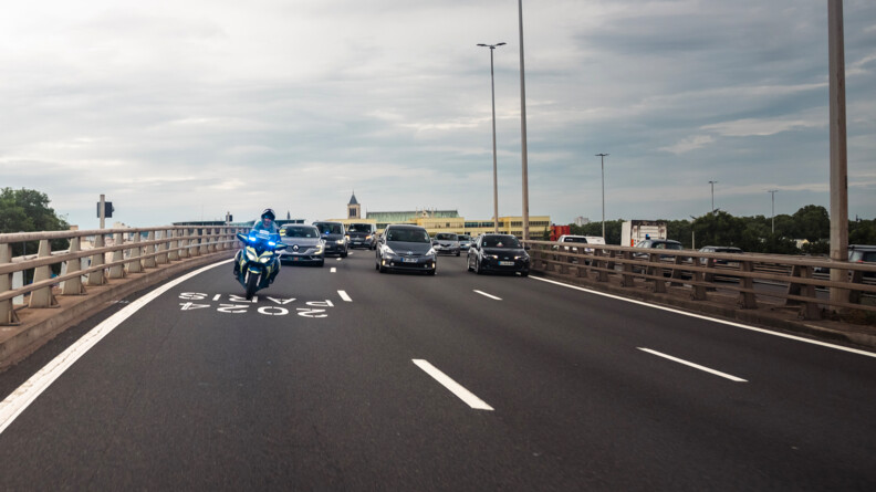 Motocycliste escortant des véhicules sur la voie réservée JOP.