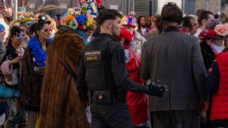 La photo repr&eacute;sente un gendarme entour&eacute; de carnavaleux, portant un d&eacute;guisement, lors du carnaval de Bergues