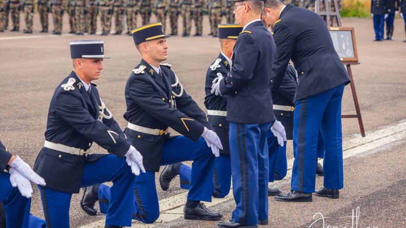 Agrandir l'image 4 élèves-gendarmes genou à terre dont deux officiers généraux retirent les galons de vareuse