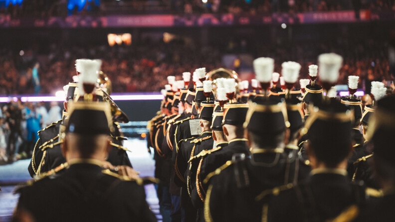 Des gardes républicains, que l'on aperçoit de dos, jouent de la musique sur la scène du stade de France