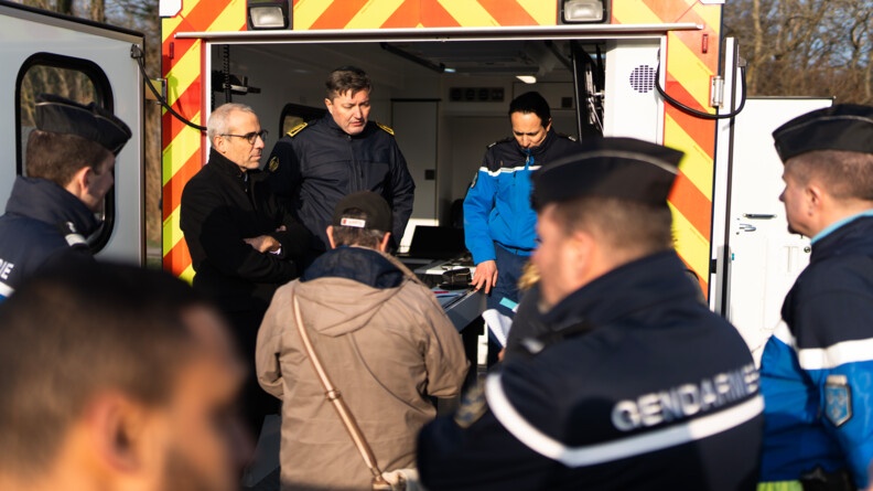 Vu sur les autorités au poste de commandement (préfet et commandant de groupement ) ainsi qu'un homme en civil. Au premier plan, flou, des gendarmes en tenue