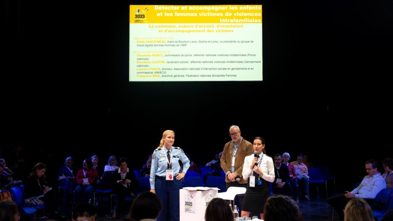 Table ronde sur les violences intrafamiliales au Salon des maires 2023, en présence des référentes sur ces violences de la gendarmerie (à gauche) et de la police (à droite) autour d'un pupitre au centre.