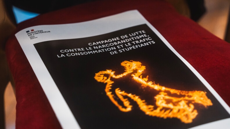 Agrandir l'image Sur l'assise rouge d'une chaise, une feuille avec l'image des contours enflammés d'une silhouette sur fond noir