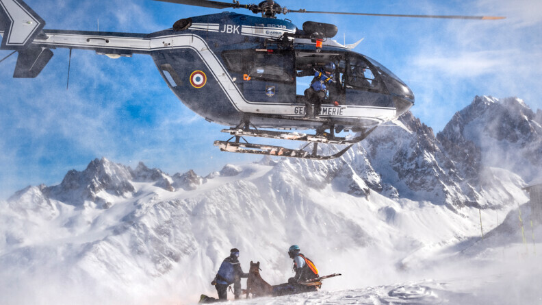 Agrandir l'image Deux gendarmes et un chien cyno en dessous d'un hélicoptère en pleine montagne.