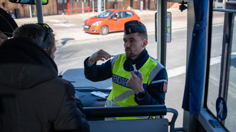 Agrandir l'image Un gendarme en train d'échanger avec un conducteur de bus à l'intérieur du bus.