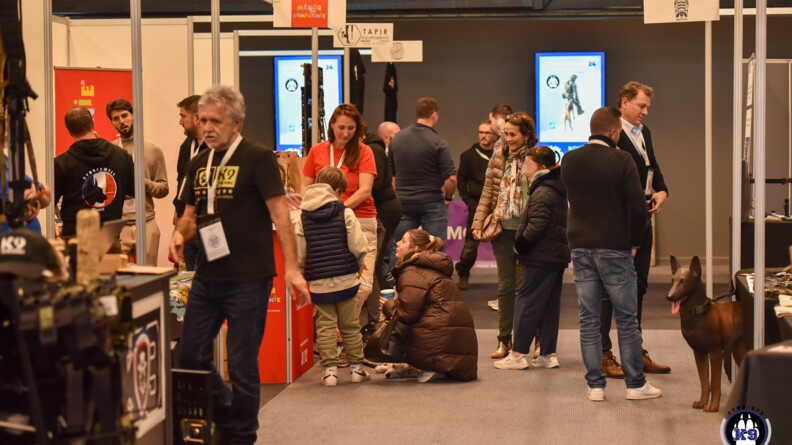 du public dans un salon d'exposant, &agrave; droite une statue de chien