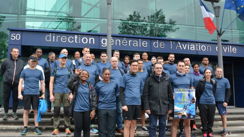 Agrandir l'image Un groupe d'une trentaine de coureurs sur les marches devant la DGAC au départ de la course