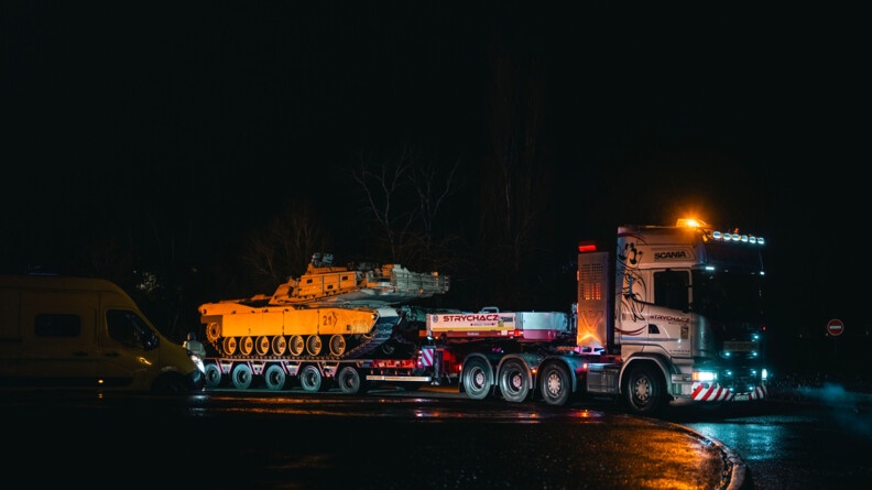 Départ du convoi. Photo du camion transportant un char. Il fait nuit et il pleut.