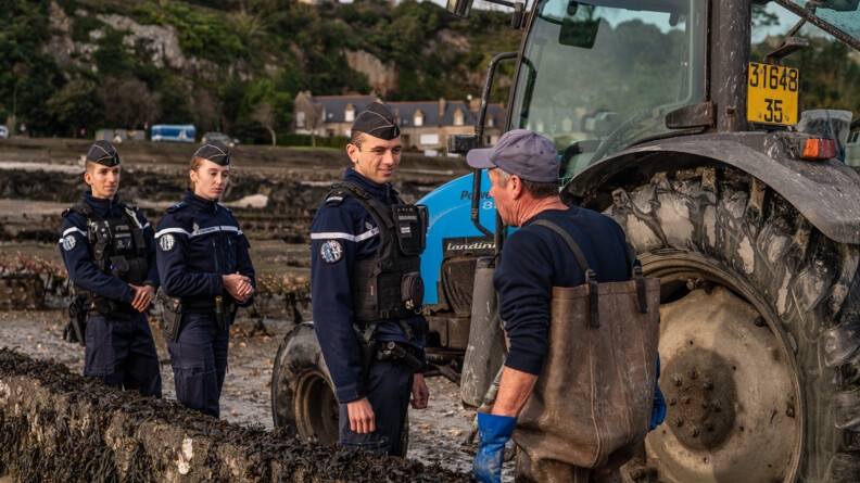 Agrandir l'image trois gendarmes parlent avec un homme dans un parc ostréicole près d'un tracteur bleu