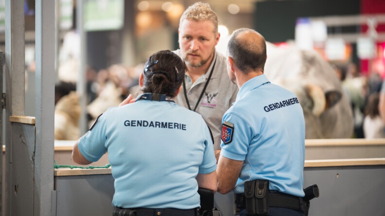 Deux gendarmes référents sûreté (de dos) échangent avec un agriculteur.