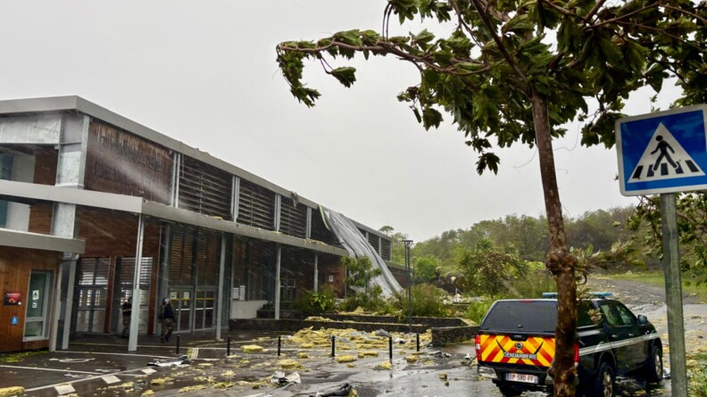 Agrandir l'image Un véhicule de la gendarmerie est stationné à proximité d'un gymnase, sur un route dévastée après le passage du cyclone Garance sur l'île de la Réunion.
