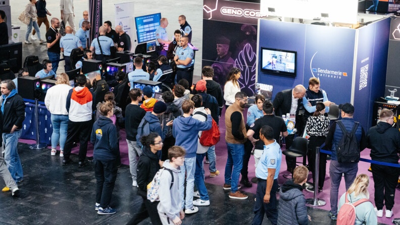 Vu en plongée sur un stand de la gendarmerie à un salon. Beaucoup de gendarmes mais aussi de jeunes