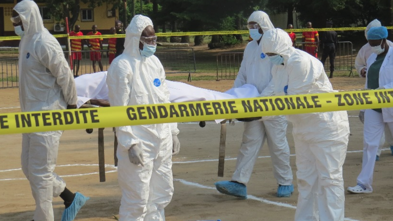 Des techniciens rev&ecirc;tant une combinaison blanche int&eacute;grale, ainsi qu'un masque et des lunettes, &eacute;voluent dans un p&eacute;rim&egrave;tre d&eacute;limit&eacute; par un ruban jaune sur lequel est &eacute;crit "Gendarmerie nationale - Zone interdite"