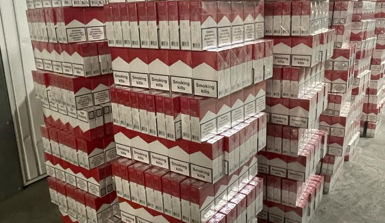 Agrandir l'image Plusieurs piles de cartouches de cigarettes dans un hangar.