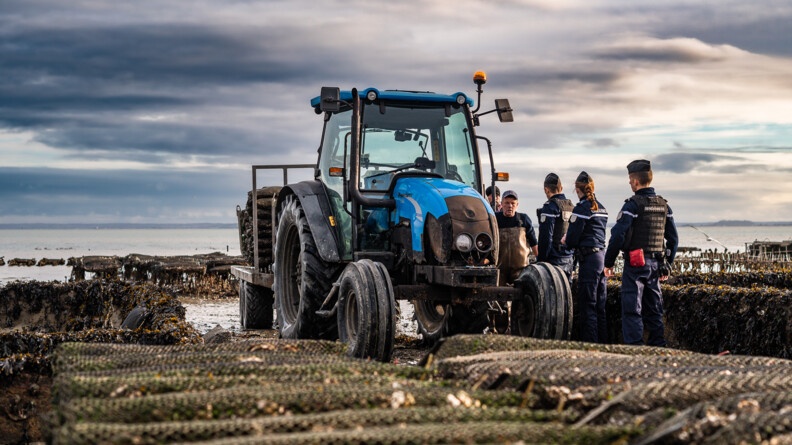 Agrandir l'image trois gendarmes parlent avec deux hommes dans un parc ostréicole près d'un tracteur bleu