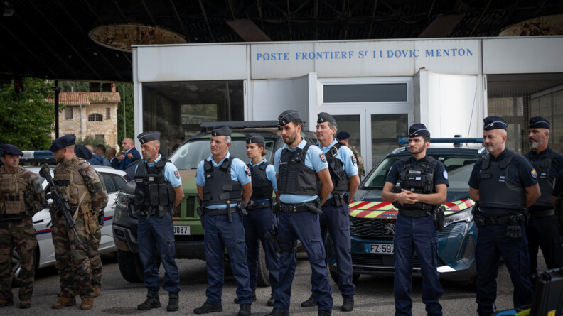 Huit gendarmes - sept hommes et une femme - se tiennent debout devant un v&eacute;hicule de la gendarmerie et un b&acirc;timent, sur la fa&ccedil;ade duquel est inscrit "Poste fronti&egrave;re Saint-ludovic Menton". A leurs c&ocirc;t&eacute;s se tiennent aussi quelques militaires de l'op&eacute;ration Sentinelle. L'un porte un fusil en travers, sur le devant du corps