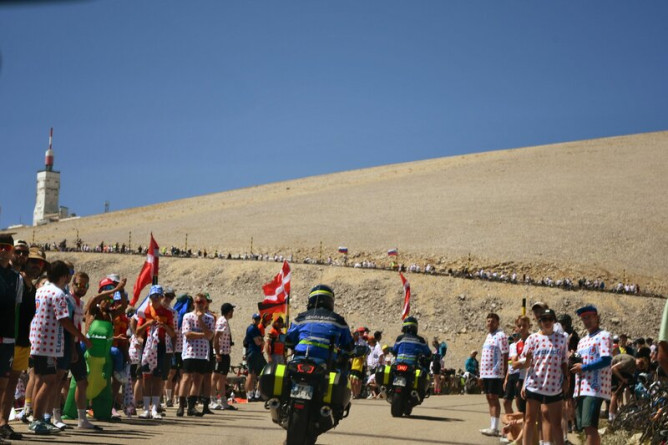 Agrandir l'image Un motocycliste de la gendarmerie roule le Mont Ventoux par un temps ensoleillé, où se touve une foule en liesse, lors d'une étape du tour de France 2025