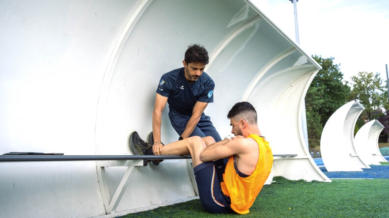 un gendarme instructeur de sport tient les jambes d'un gendarme en train de faire des abdominaux.