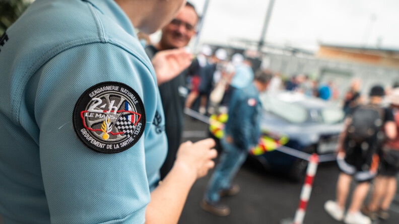 Agrandir l'image Rondache 24h du Mans. C'est une roue avec au centre écrit 24h du Mans avec le tracet du circuit en rouge, la grenade de la gendarmerie et le drapeau à damier et français à côté de la grenade.