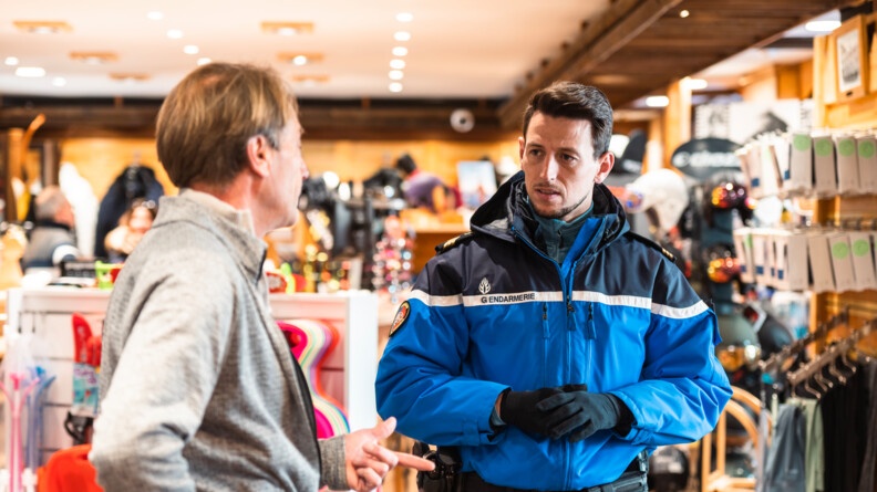 Dans un magasin de vêtement de ski, un gendarme parle avec un commerçant.