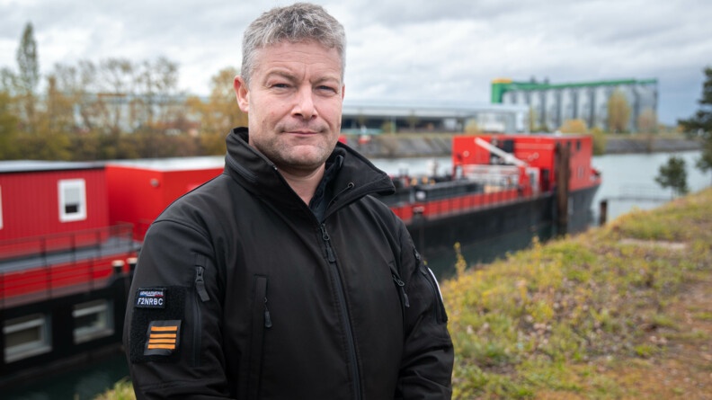 Portrait du CEN Péré, commandant la F2NRBC avec la péniche en arrière plan