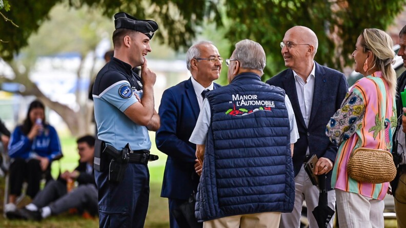 A gauche, un gendarme qu discutent avec un groupe composé de trois hommes et une femme, tous souriants