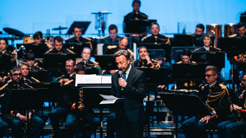 Stéphane Bern lit un docuemnt au micro devant l'orchestre de la Garde républicaine