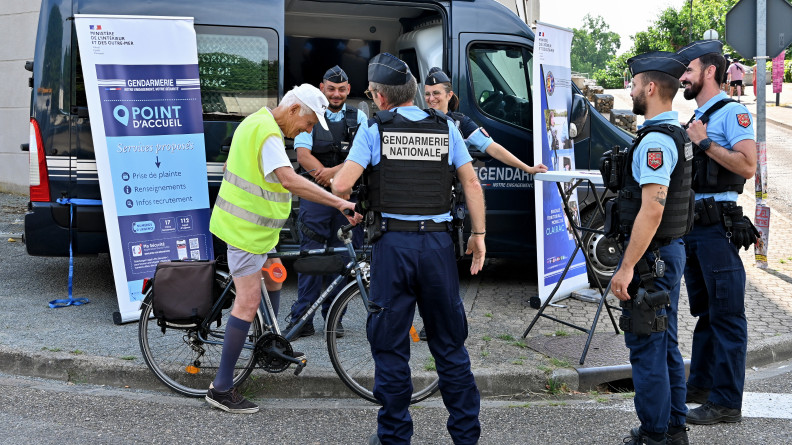 Cinq gendarmes échangent avec un cycliste vêtu d'une chasuble jaune, au niveau d'un point d'accueil de la gendarmerie signalisé par un kakémono, à l'occasion du festival Garorock