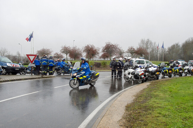 Agrandir l'image Des motocyclistes de la gendarmerie et de la police, sur leurs motos et à pied, bloquent un rond-point.