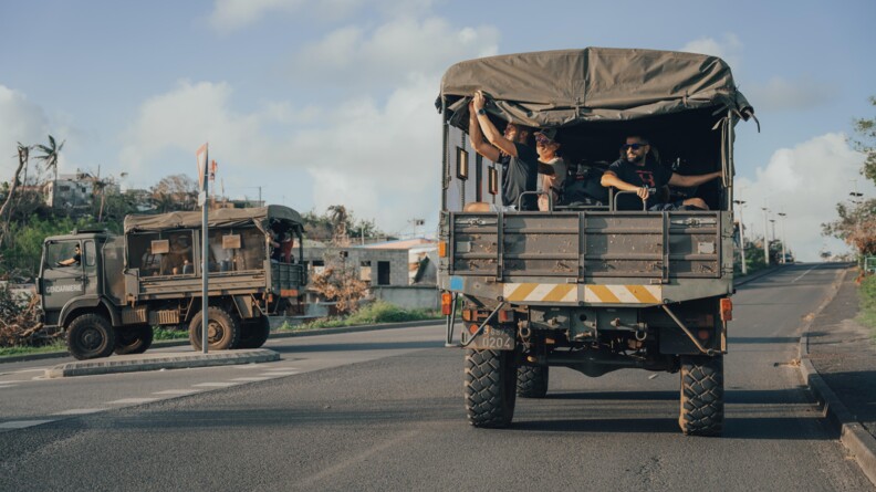 Deux camion militaires de transports de troupe, un tournant à gauche et l'autre sur la route, transportant des personnels