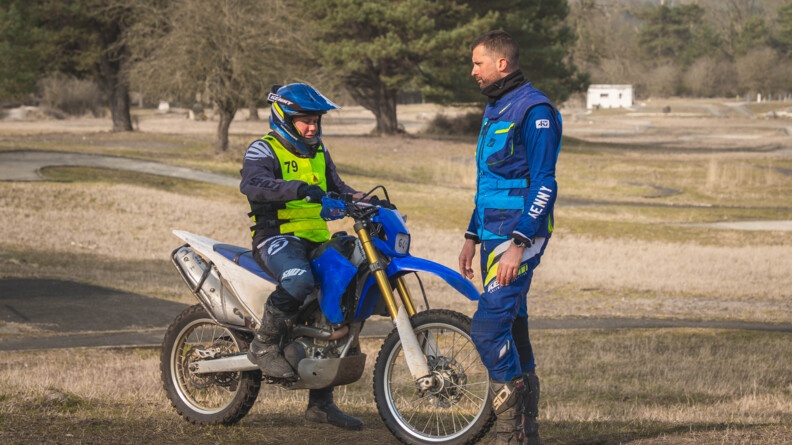 Une motarde de la gendarmerie face à son instructeur sur un terrain sauvage avec quelques arbres