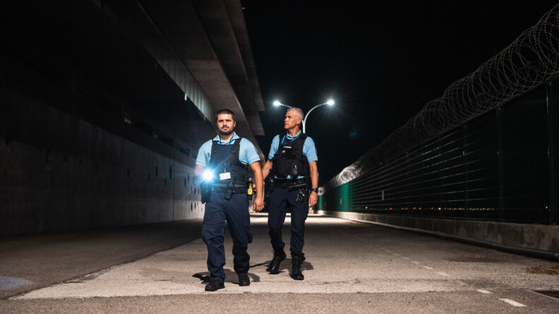 Dans la nuit et en extérieur, deux gendarmes de l'armement réalisent une patrouille.