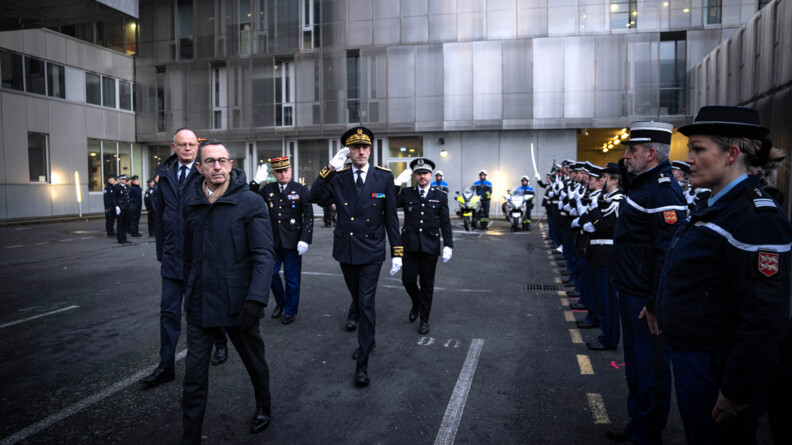 Le ministre de l'Intérieur, suivi des autorités civiles et militaires, passe les troupes en revue. A droite de l'image, une rangée de gendarmes au garde-à-vous. Dans le fond, des motocyclistes, pied à terre.