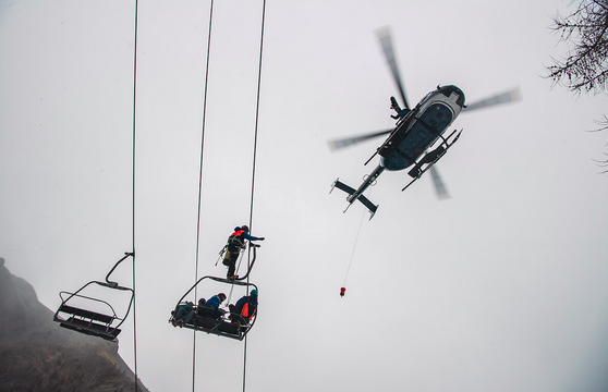 Un hélicoptère de la gendarmerie survole un télésiège, sur lequel sont bloqués des skieurs, au cours d'une opération de sauvetage.