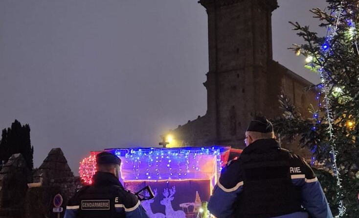 Deux gendarmes au pied d'une église devant des décorations de Noel