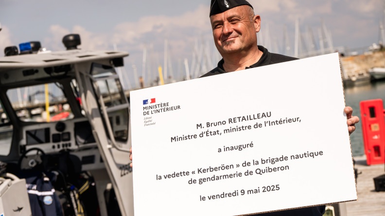 Agrandir l'image Gendarme tenant un panneau affichant "M. Bruno Retailleau, ministre d'État, ministre de l'Intérieur, a inauguré la vedette "Kerberöen" de la BN de gendarmerie de Quiberon le vendredi 9 mai 2025"