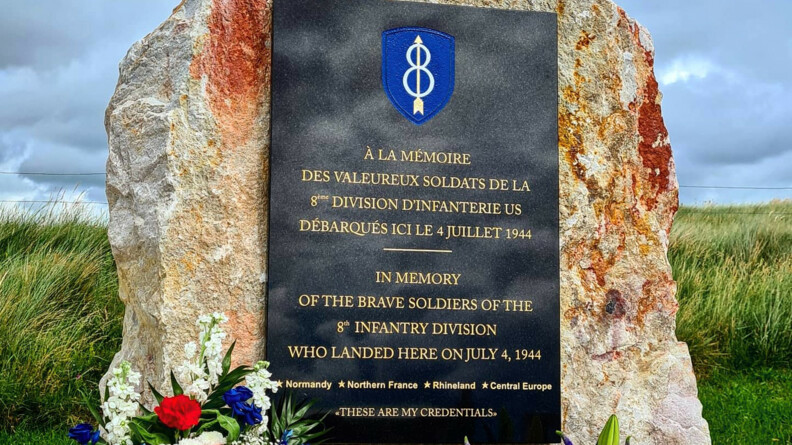 Agrandir l'image Un monument commémorant la 8e division d'infanterie américaine. au sol une gerbe de fleurs à gauche aux couleurs du drapeau français, à droite à celle du drapeau américain