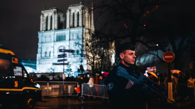 Un gendarme mobile pose devant la cath&eacute;drale. Il fait nuit .