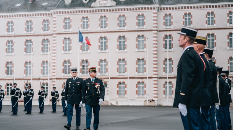 Agrandir l'image Un général de gendarmerie, suivi par un colonel, passe en revue ses troupes sur une place d'armes devant un bâtiment d'etat-major