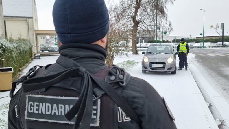 De dos, un gendarme mobile. Il est tourné vers un contrôle routier par deux gendarmes sur un véhicule gris foncé