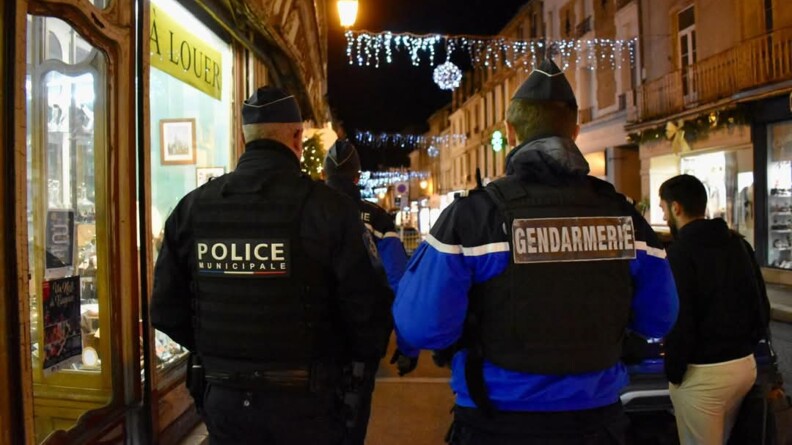 Un gendarme et un policier municipal de dos dans une rue décorée pour Noël