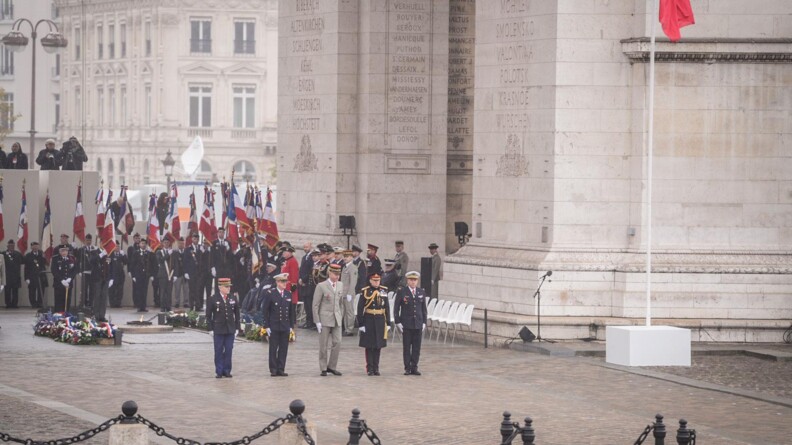 Agrandir l'image 5 autorités mitaires alignées devant l'arc de Triomphe où se trouvent des troupes avec étendards
