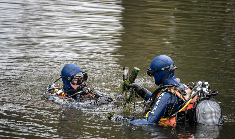 Agrandir l'image Deux plongeurs gendarmerie, la tête hors de l'eau, en train de remonter des bouteilles en verre.