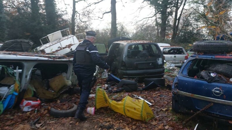 Un gendarme se déplace au milieu d'un champ de véhicules épaves