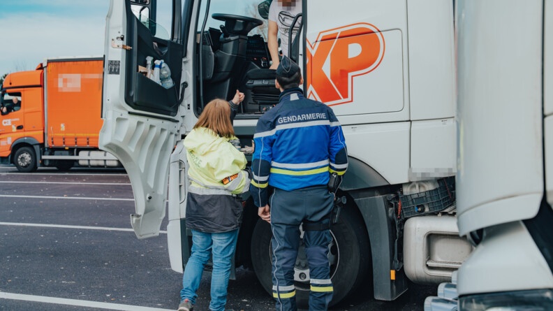 Un gendarme et une agent des douanes, controlent un camion.