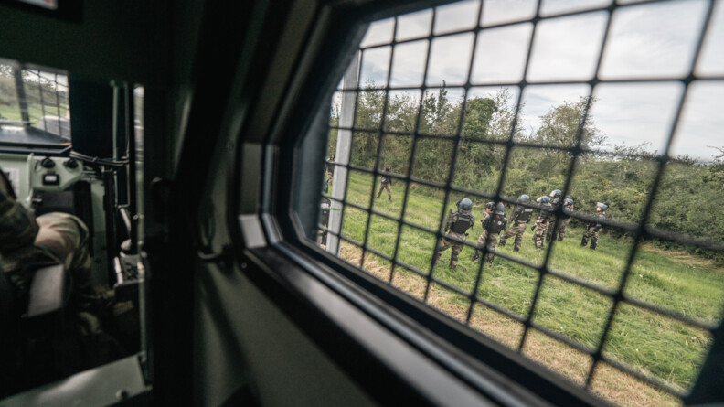 Agrandir l'image De l'intérieur du véhicule, l'on observe les forces mobiles qui se mettent en place à l'extérieur pour protéger une zone. Tout cela se déroule de jour dans un environnement de campagne.